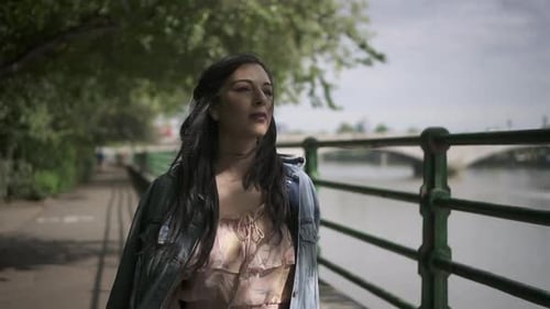 Slow Motion of an attractive latina tourist with black wavy hair and a jean jacket walking in a park