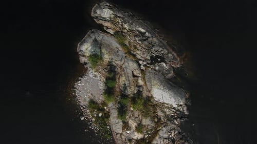 Waves Wash Small Island with Lush Green Trees and Rocks