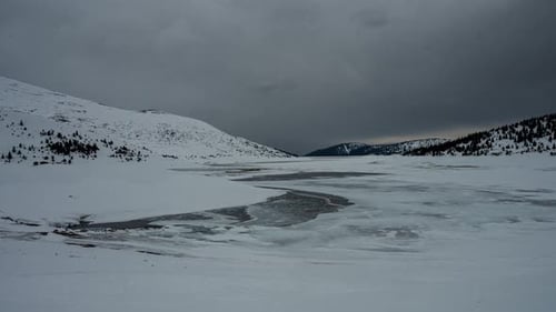 Moving heavy clouds over the frozen mountain lake