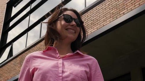 Business Woman in Sunglasses Stands Against the Background of a Modern Building