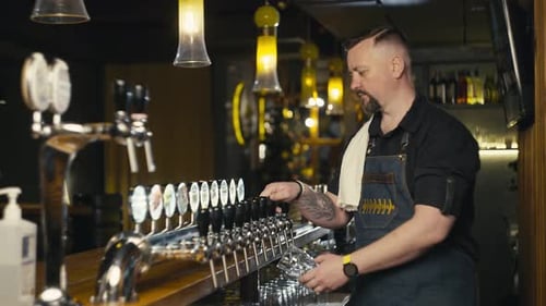 The Bartender Pours Beer Into a Glass on the General Plan