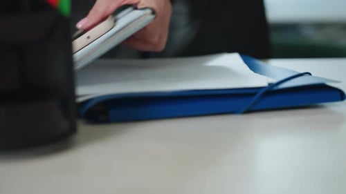 Close Up of Folder with Phone and Laptop on Modern Office Desk