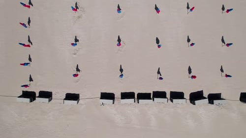 Aerial top down, rows of closed beach umbrellas during summer. Vacation holiday relaxation concept
