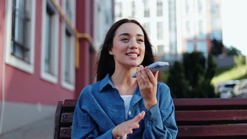 Young Woman Recording Voice Message in City Park