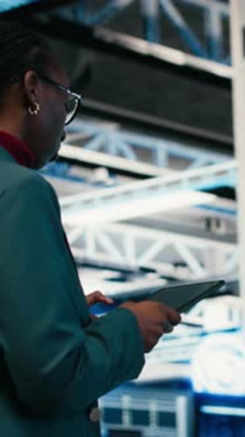 Vertical Video Writing Code Tablet and Female Programmer Walking in Data Center