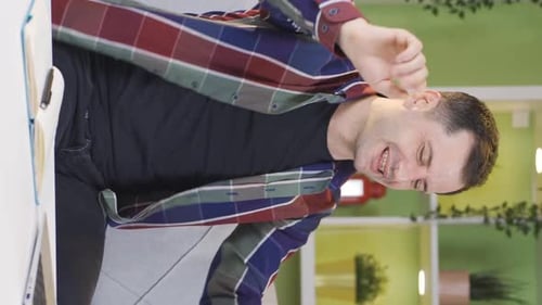 Vertical Video of The man with the laptop in front of him starts dancing while looking at the screen