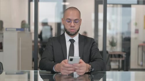 Focused Business Man Using Smartphone in Modern Office
