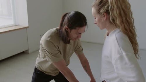 Choreographer Explaining Dance Move to Young Woman in Studio