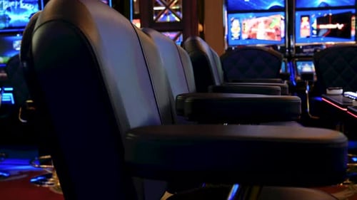 Slider shot of bright slot machines inside a casino display vivid screens with comfortable chairs