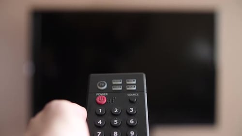 First person view of turning on a TV with a remote control in front of a chroma keyed, green screene