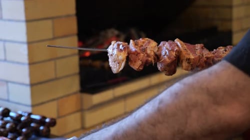 Closeup of a Chef Wearing Gloves Stringing Marinated Pork Meat on a Skewer