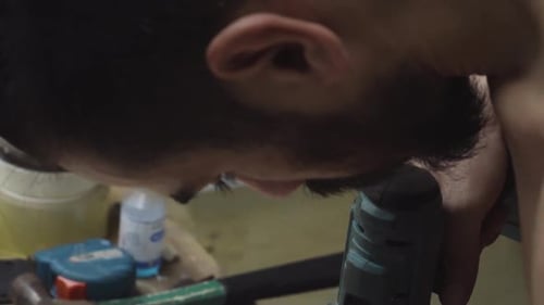 Skateboard Maker Drilling Holes On Wood Plank Using A Cordless Driller. close up, tilt down