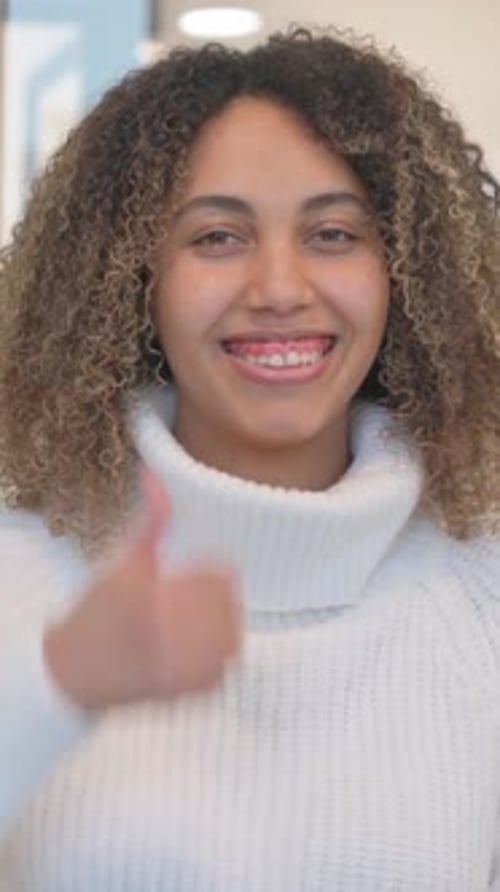 Smiling Woman Gives Thumbs Up Wearing White Sweater
