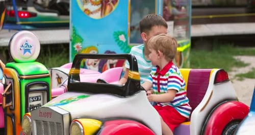 Two Happy Child Having Fun on Toy Car at an Amusement Park