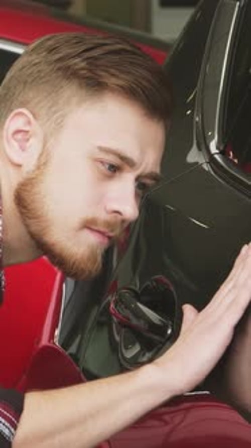 Handsome Bearded Male Customer Examining Car Paint on a New Auto at the Dealership