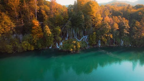 Türkisfarbenes Wasser in einem Bergwaldsee mit leuchtenden Herbstbäumen. Luftaufnahme des Wasserfalls in Gold