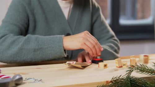 Woman crafting Christmas decorations on wooden table indoors