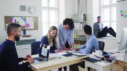 Colaboração de jovens equipes de negócios em torno de um laptop em um espaço de escritório moderno