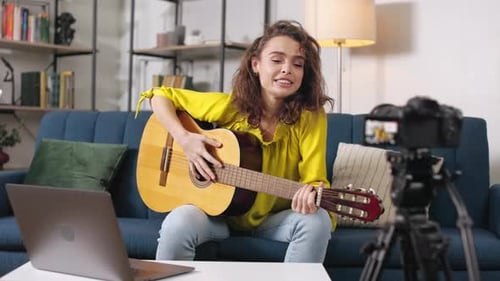 Tutorial de guitarra para filmación femenina con portátil y cámara para interiores