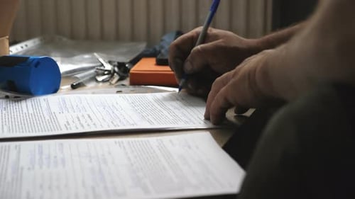 Person filling out paperwork with blue pen