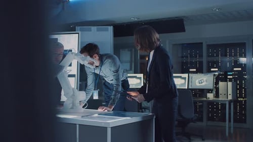 Engineers Analyzing Robotic Arm in Modern Office