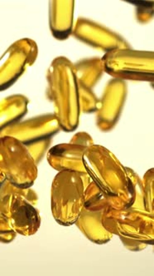 Las cápsulas de vitamina Omega 3 suben y bajan filmadas en cámara lenta a 1000 fps