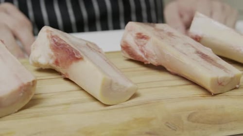 Moelle osseuse avec taches de sang placée sur une planche à découper en bois.