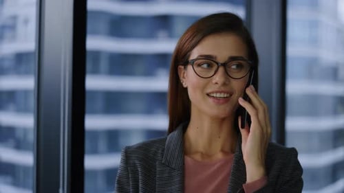 Cheerful businesswoman smiling while talking on her mobile phone in the office