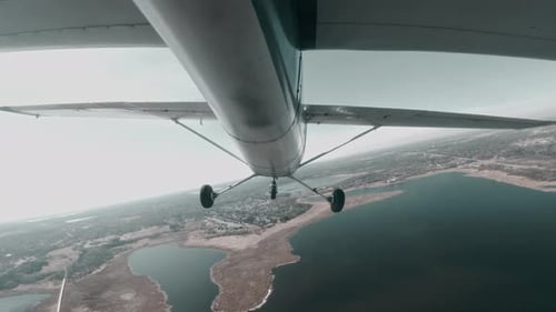 Avion léger Cessna 150 s'inclinant au-dessus d'un lac et d'un paysage suburbain