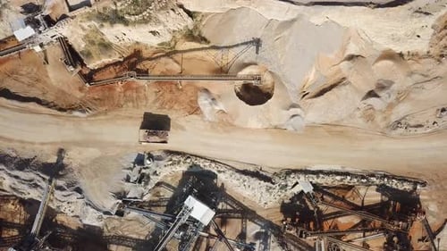 large Quarry during work hours with Stone sorting conveyor belts and an open pit mine.