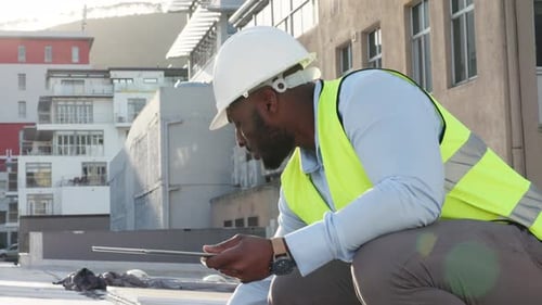 Professional male foreman or contractor inspecting a building and adding updates on a tablet