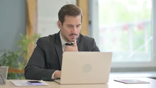 Man Concentrating on Laptop in Office Workplace