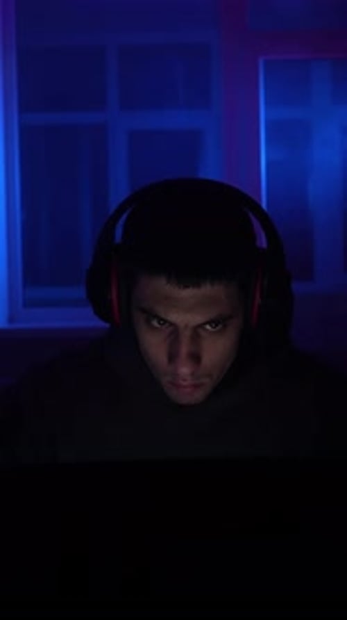 Young Adult Gamer Immersed in Dark Blue Room