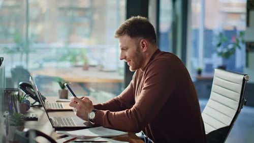 Smiling Executive Reading Cellphone Message in Modern Office Interior Closeup