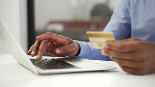 Close up of male hands typing on laptop to make online transaction with credit card at desk