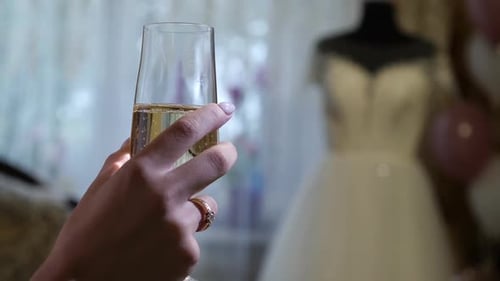 54s. Mulher segurando uma taça de champanhe no fundo de um vestido de noiva
.