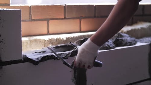 Builder Applying Mortar to White Brick