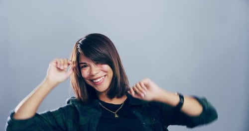 Woman Dancing and Smiling in Front of Grey Background
