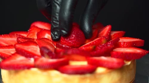 Close Up of a Pastry chef placing the last strawberry on top of a custard cream filled tart
