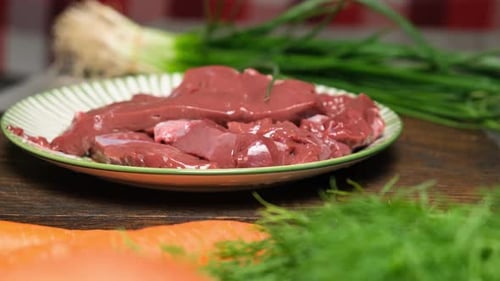 The Camera Moves Past Fresh Beef Liver Cut Into Pieces on a Flat Plate Cooking Liver with Fresh