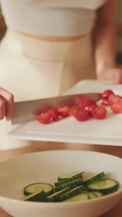 Close-up of young woman's hands preparing salad at home in the kitchen