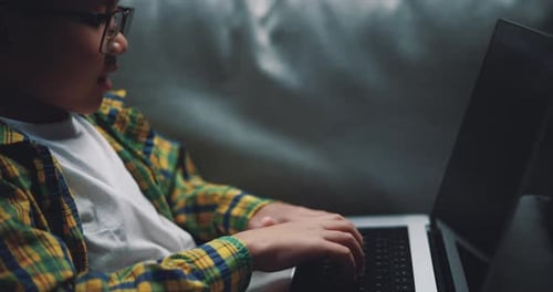 Asian boy wearing glasses schoolboy using a laptop computer