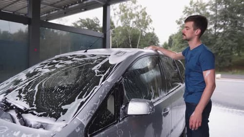 Man Washing a Car with Sponge and Soap