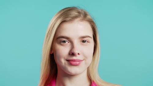 Young Charming Blonde Woman with Kind Smile Looking to Camera on Blue Studio