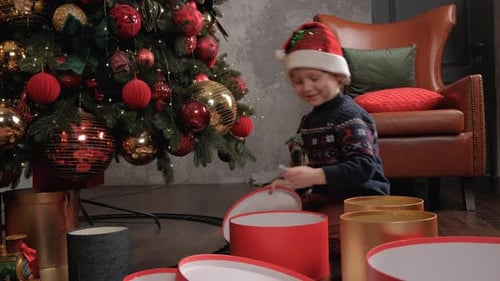 Child Opens Christmas Present Near Christmas Tree