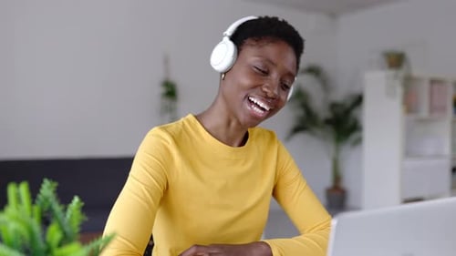 Smiling Woman on Laptop Video Call with Headphones