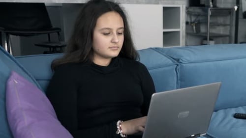Teenage Girl Using Laptop on Blue Sofa