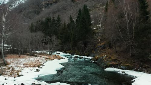 Peaceful Winter Stream Flowing Through A Snow Dusted Mountain Forest