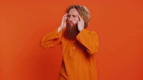 Man with Headache Against Orange Background