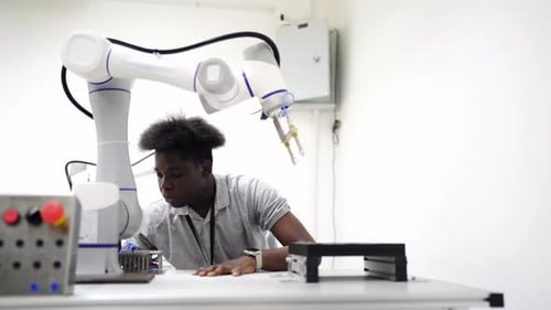 Robotics engineer fitting sensors to traditional engineering Robot Arm in robotics research facility